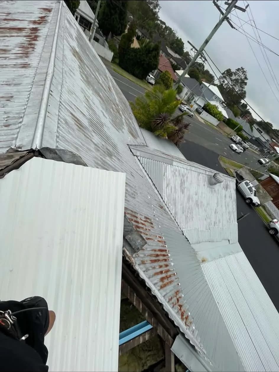 Rusted old roof sheets beside new Colorbond sheets during a metal re-roof