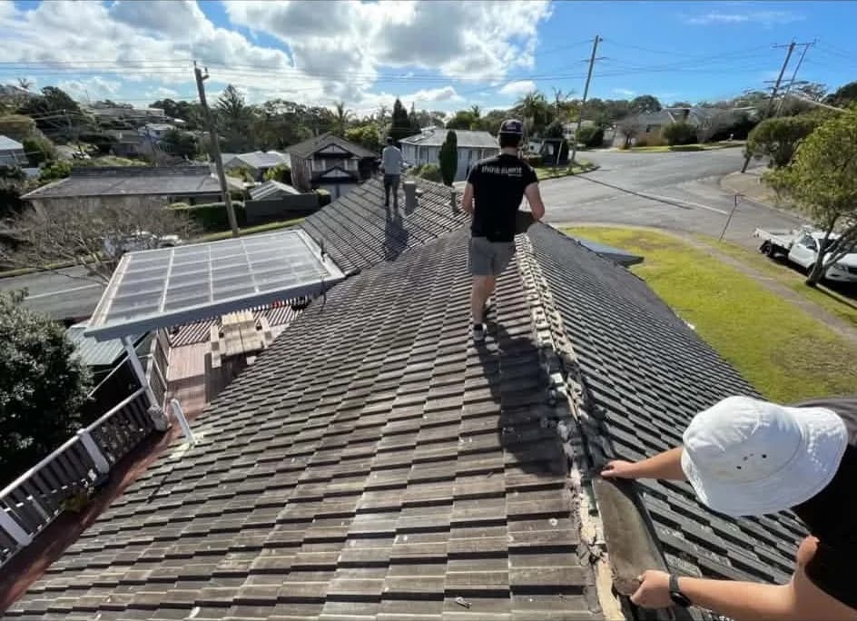 Roofing crew stripping the tiles off a house roof